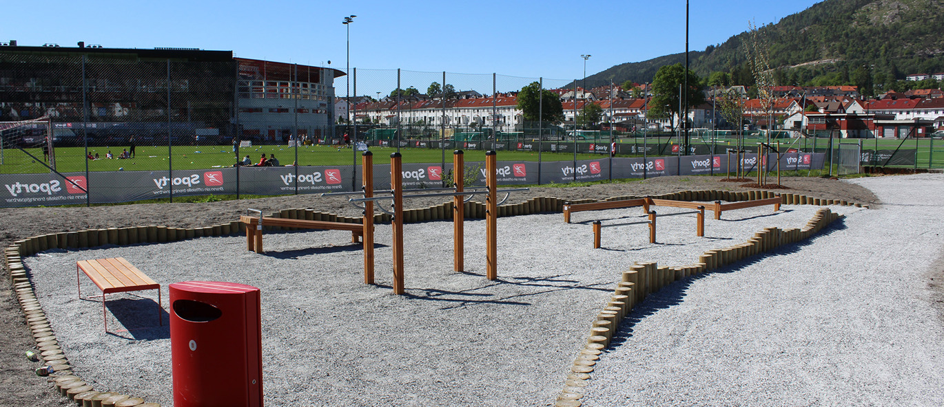 Träningsredskap av trä på grusunderlag vid en idrottsplats.