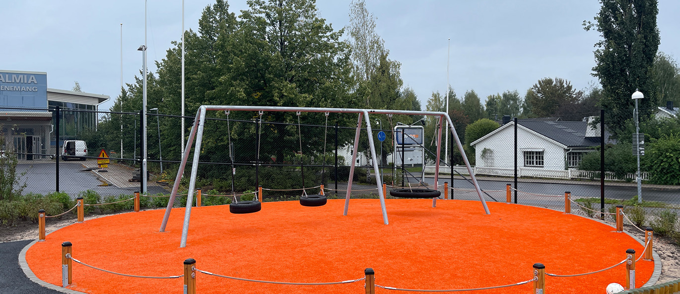 Gungställning med tre gungor på ett orange konstgräs omgivet av ett litet lekplatsstaket.