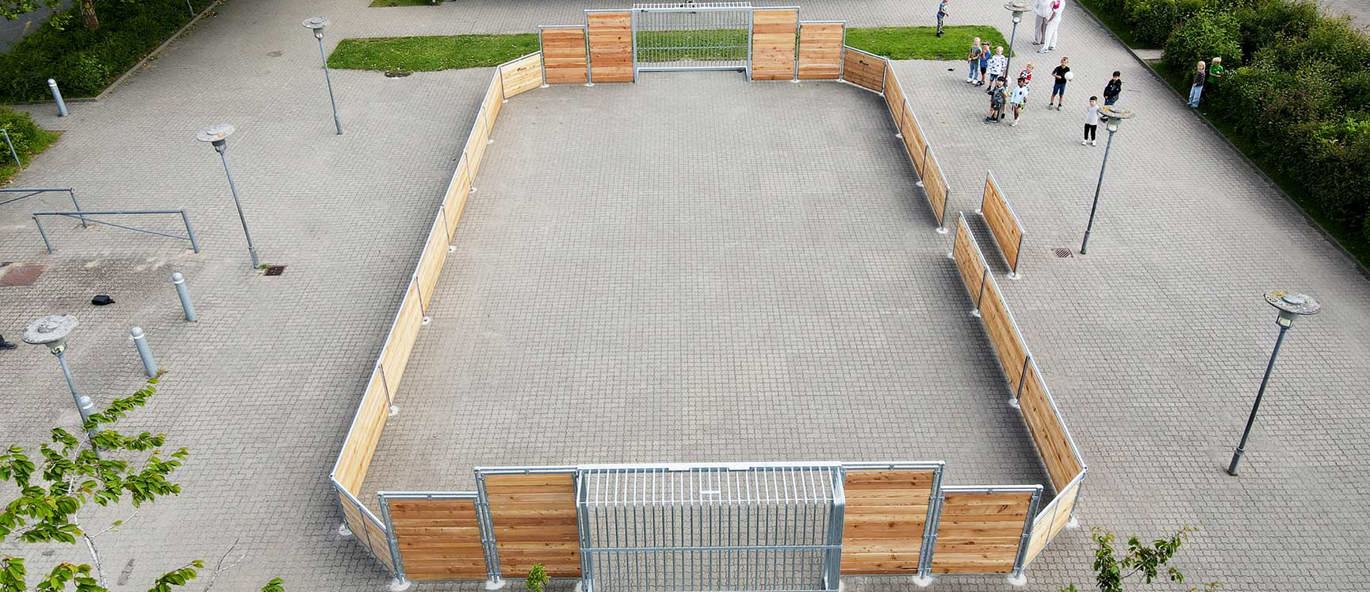 skolgård sedd ovanifrån med plattsättning och en multiarena i lärk i centrum, en annan multiarena i bakgrunden samt ett cykelskjul