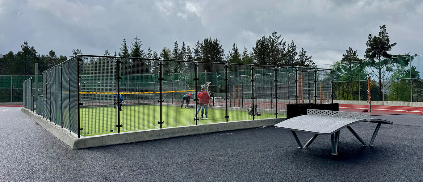 Bollbana med grönt konstgräs och Archball Multispelbord på asfalten framför.