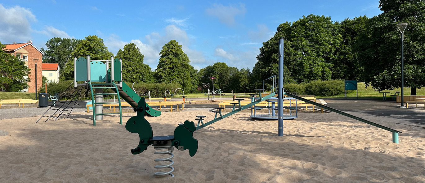 Lekplats med grusunderlag och många olika lekredskap, bland annat en fjädergunga och klätterställningar.